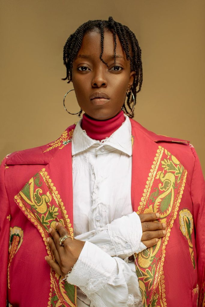 Young black woman in dreadlocks wearing red costume resembling uniform